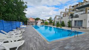 a swimming pool with white lounge chairs next to a building at Airport Bea in Otopeni