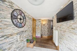 a large clock on a brick wall with a television at Antico Mulino Hotel Garni in Todtmoos
