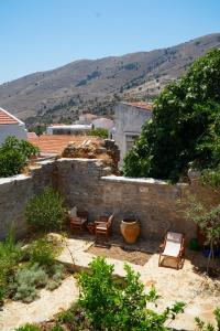 a patio with chairs and tables and a building at Symi Uptown Indigo in Symi