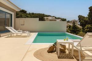 a swimming pool with a table and chairs next to a house at Villa Dido - Zen Villas in Fiskardho