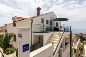 une maison blanche avec des escaliers et un parasol dans l'établissement Guest House Kono, à Dubrovnik
