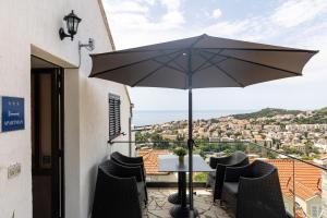 une table et des chaises avec un parasol sur un balcon dans l'établissement Guest House Kono, à Dubrovnik