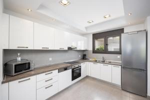 a kitchen with white cabinets and a stainless steel refrigerator at Villa Dionysos in Lachania
