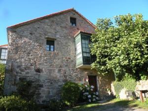 an old stone building with a tree in front of it at Fogar dos Antigos in Mazaricos