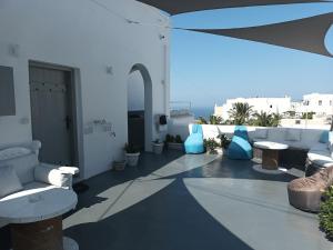 un patio con sedie, tavoli e un ombrellone di Ichor Suites a Firà