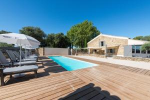 a pool with chairs and an umbrella next to a house at Le Mas des Aracil 2 - Appt climatisé avec piscine in Suze-la-Rousse