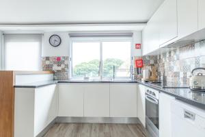 a kitchen with white cabinets and a clock on the wall at Viriato's House in Ribeira Grande