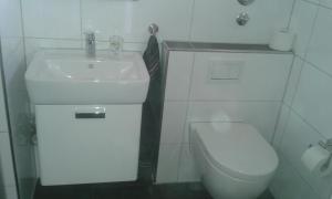 ein weißes Bad mit einem Waschbecken und einem WC in der Unterkunft Ferienwohnung Steffens Hahnenklee in Hahnenklee-Bockswiese