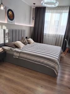 卡拉甘达Муканова 6的卧室里有一张大床，床上铺着条纹毯子