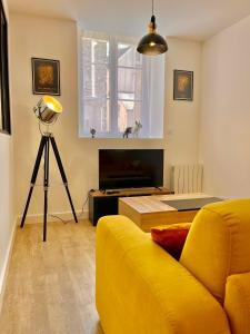 sala de estar con sofá amarillo y TV en T2 Rez-de-chaussée, Le Victor Hugo, en Cancale