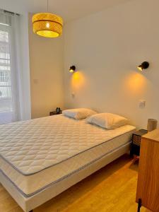 Un dormitorio con una cama grande con sábanas blancas. en T2 Rez-de-chaussée, Le Victor Hugo, en Cancale