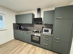 a kitchen with gray cabinets and a microwave at SeeHausLuwiRoyal in Ludwigswinkel