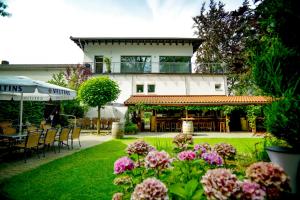 einen Garten mit Tischen, Stühlen und Blumen in der Unterkunft Hotel Restaurant Kohlbrecher Villeroy & Boch SPA in Osnabrück