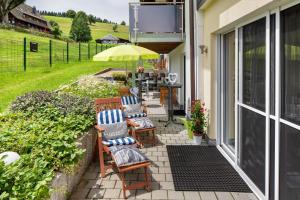 a patio with chairs and an umbrella on a house at Fewo Schwarzwaldflair mit Eventraum in Hofsgrund