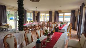 a restaurant with tables and chairs with red and white tablecloths at Pension Achterland in Mellenthin