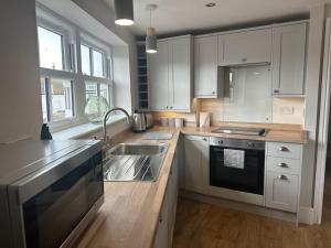 Una cocina con gabinetes blancos, un fregadero y una estufa. en Church walk view apartment Filey, en Filey