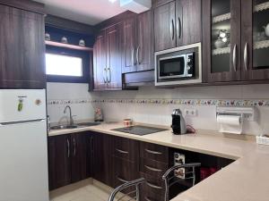 a kitchen with wooden cabinets and a sink and a microwave at Puesta de Sol in Punta del Hidalgo