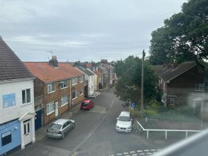 Una calle de la ciudad con coches aparcados en la calle. en Church walk view apartment Filey, en Filey