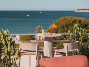a table with a drink and chairs on a balcony at Hôtel Liautaud Rooftop Cassis in Cassis