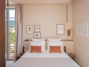 a bedroom with a white bed with two orange pillows at Hôtel Liautaud Rooftop Cassis in Cassis