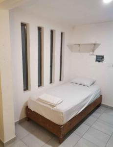 a bed in a room with a white wall at LaNegra in Cancún