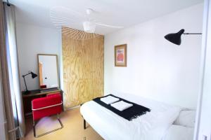 a bedroom with a bed and a mirror and a red chair at Bright & Eco-Friendly Wooden Home, A Peaceful Retreat Near Paris in Montreuil +8 photos