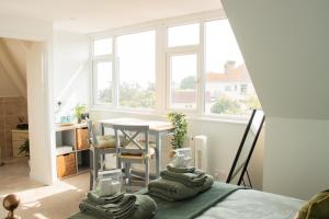 a room with a bed and a table and windows at B’s Place Guest House in Paignton