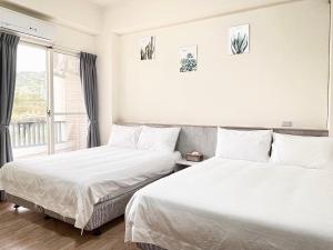 zwei Betten in einem Zimmer mit Fenster in der Unterkunft Hui Chao Gui Su in Taitung