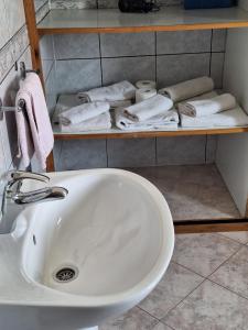 a bathroom with a sink and a shelf with towels at Loft Apartman in Krk +16 photos
