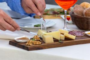 a person cutting cheese on a cutting board with a fork and knife at Allegroitalia La Spezia 5 Terre in La Spezia