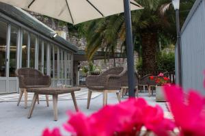 patio z krzesłami, parasolem i różowymi kwiatami w obiekcie Allegroitalia La Spezia 5 Terre w mieście La Spezia