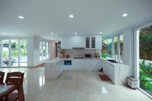 a large kitchen with white cabinets and windows at Xanh Villa Resort 5 Stars in Nam Giao