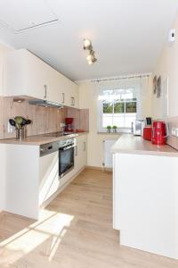 eine Küche mit weißen Geräten und Holzböden in der Unterkunft Ferienwohnungen und Ferienhaus Polmann in Nordwerdum in Werdum