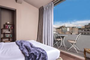 a bedroom with a bed and a balcony with a table at iFeel Athens Suites in Athens