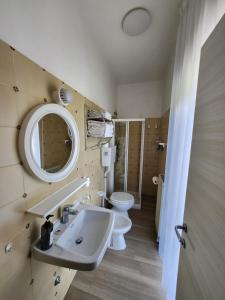 un bagno con lavandino, water e specchio di Casa Beniamino a Riva del Garda