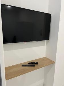 リヨンにあるT2 moderne à 10 min du centre-ville de Lyonの壁にテレビがかかっており、棚の上にはリモコンが 2 つ置かれている