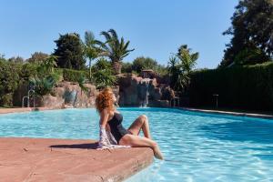 una mujer sentada en el borde de una piscina en TAIGA Tarifa Punta Paloma, en Tarifa