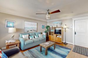 a living room with a blue couch and a tv at Cottage House #103 in Corpus Christi