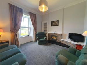 a living room with chairs and a fire place at Little Bay View in Oban