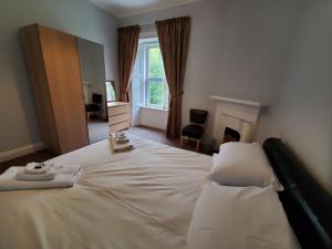 a bedroom with a large white bed with a window at Little Bay View in Oban
