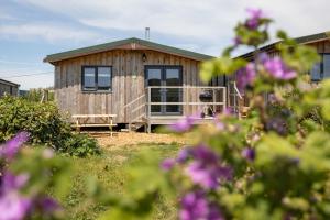 a wooden cabin with a porch in a yard with flowers at West Chalet At Tapnell Farm in Yarmouth