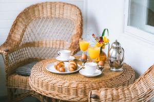 a rattan table with a breakfast of croissants and orange juice at Vila Šilelis in Palanga