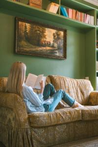 a woman sitting on a couch reading a book at Vila Šilelis in Palanga