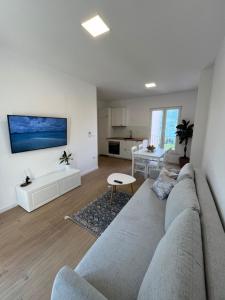 a living room with a gray couch and a kitchen at Apartments Laura in Korčula
