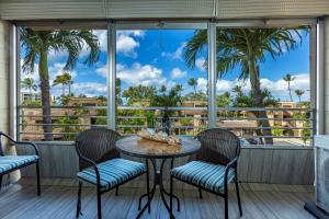 a patio with a table and chairs and palm trees at Kamaole Beach Royale 208 in Kihei