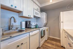 a kitchen with white cabinets and a sink and a refrigerator at Kamaole Beach Royale 208 in Kihei