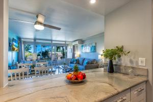 a kitchen and living room with a bowl of fruit on a counter at Kamaole Beach Royale 208 in Kihei