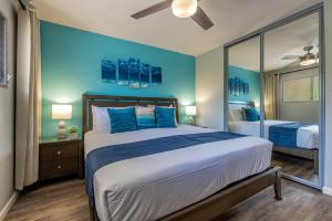 a bedroom with a large bed with a blue wall at Kamaole Beach Royale 208 in Kihei