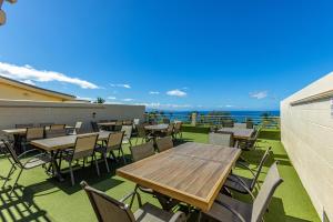 a patio with tables and chairs and the ocean at Kamaole Beach Royale 208 in Kihei