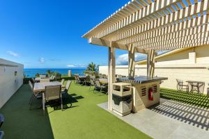 an outdoor patio with tables and chairs and a grill at Kamaole Beach Royale 208 in Kihei
